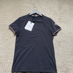 Moncler T-shirt - Säljer min moncler t-shirt, den i bra skick. Storlek S. Tröjan är i färgen navyblue. Skick 7,5/10. Har tags men har tyvärr inget kvitto. Hör gärna av dig om du har frågor!