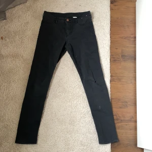 Jeans - Svarta stretchiga jeans med ett pytte litet hål på knät 