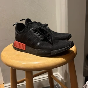Addidas NMD röd och svart - Addidas nmd med röd svart färg, 8/10 skick, är jävligt sköna och har en väldigt bra sula. Bra för alla vardags aktiviteter.