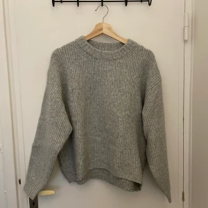 Stickad tröja - En grå stickad tröja, rätt tjock och kompakt. Köpt på HM, står storlek S Men den är rätt stor och lite oversized så skulle säga att den mer ös som storlek M. Det har gått en maska (se bild tre), lätt att laga och kommer inte synas. Kliar inte 