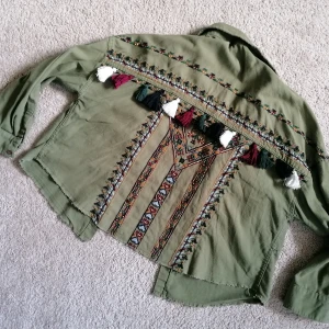 Shirt - Khaki shirt with frills and embroidery. Oversized fit, can be worn by someone who is between size S - L. Shirt is made of 100% cotton and embroidery 100% polyester. 