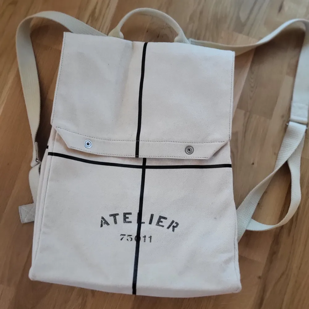 Authentic bag. Maison Martin Margiela backpack in beautiful offwhite canvas with 'Atelier' print. Very good condition, except for one backstrap that is fraying. I'm happy to send additional pics.. Väskor.