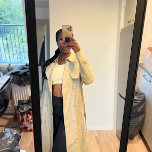 Lång trenchcoat i ”läder”  - Krämfärgad coat i ormimitation. Använd 1 gång