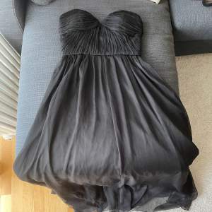 Svart balklänning från Gina Tricot i storlek XS. Den ser grå ut på videon men är mörkare (svart) i verkligheten. Har inga fläckar eller liknande. Går ner till golvet.