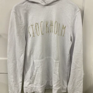Vit tjocktröja  - Vit tjocktröja med ”Stockholm” tryckt på bröstet. ”S:et” på Stockholm är lite slitet