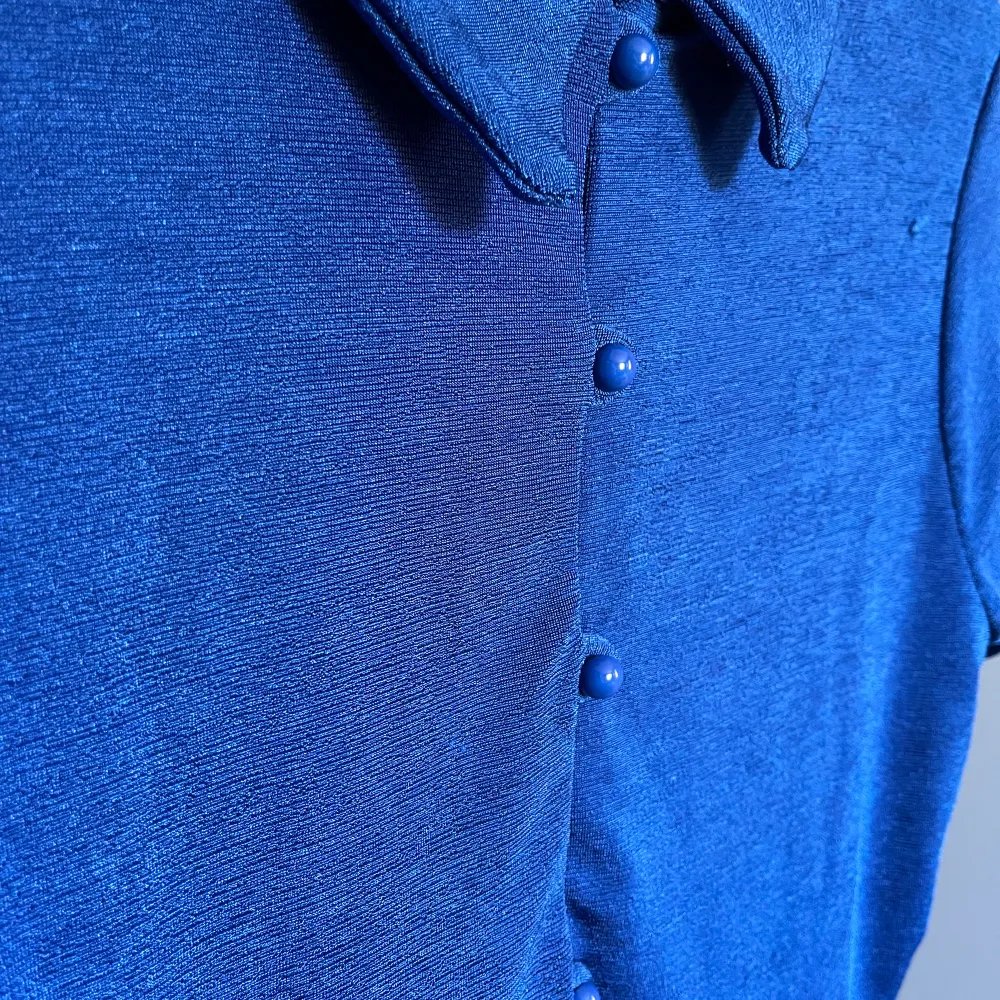 Kornblå top med knäppning i super skönt ”sladdrigt” material. Croppad modell passar allt imellan S-L. Toppar.