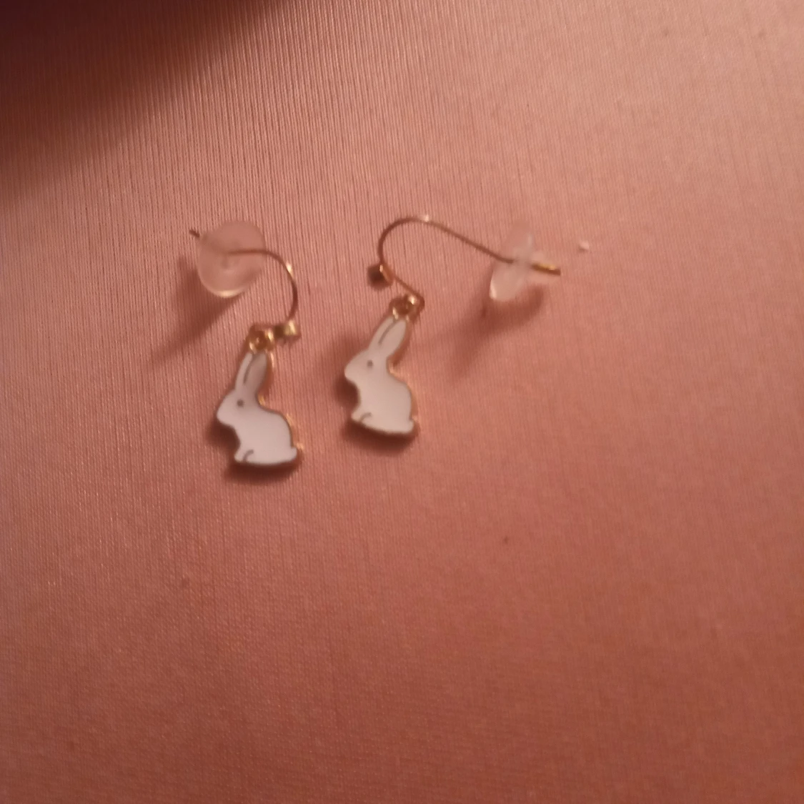 Guldfärgade örhängen med hänge av Olle kanin samt en kristall .