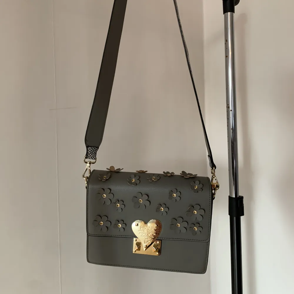 Väldigt fin grå väska med unik modell. Blommor och gulddetaljer. Passar till allt men används tyvärr inte. Fint skick. . Väskor.