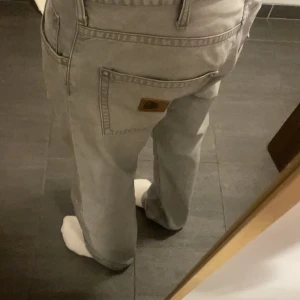 Carharrt Grå Jeans - Gråa Jeans från Carharrt. Väldigt lika de ljusgrå från hope, i färg och passform. Nyskick, knappt tecken på användning, inga slitningar längst ner men faller ändå snyggt över skorna. Säljer då jag tyvärr växt ur dem. De har L34