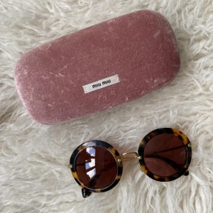 Miu miu solglasögon - Miu miu solglasögon med fodral, en lös pigg (se bild två) men går nog att fixa, och en liten repa på ena glaset men inget man tänker på. Nypris över 3000 kr. 