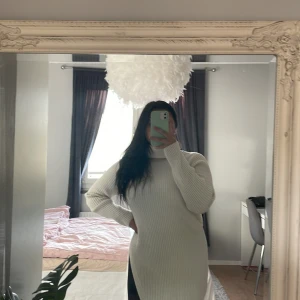 Stickad klänning med slits - Beige/vit stickad klänning med slits på ena sidan, klänningen är ribbad. Strl xs