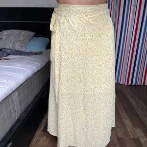 Blommig Kjol - Gul blommig omlottkjol. Storlek S/36.