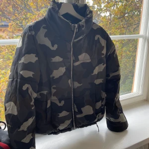 Kamouflage dunjacka  - Kamouflage dunjacka i gröna toner, resor i midjan man kan anpassa  
