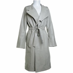 Trenchcoat läder - Hej! Säljer denna snygga trenchcoat i läderimitationen köpt på Sellpy. Aldrig använd, den är i en grå/grön färg.