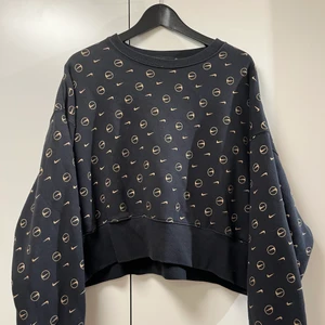 Nike, stl S - En svart croppad Nike sweatshirt med guldiga Nike märken över hela. Lite oversize, storlek S.
