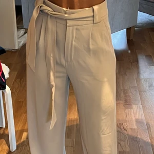 Ljusbeiga kostymbyxor från H&M - Ljusbeiga kostymbyxor från H&M. Använt enstaka gånger. Bra skick. Bältet går att ta bort. Storlek 36