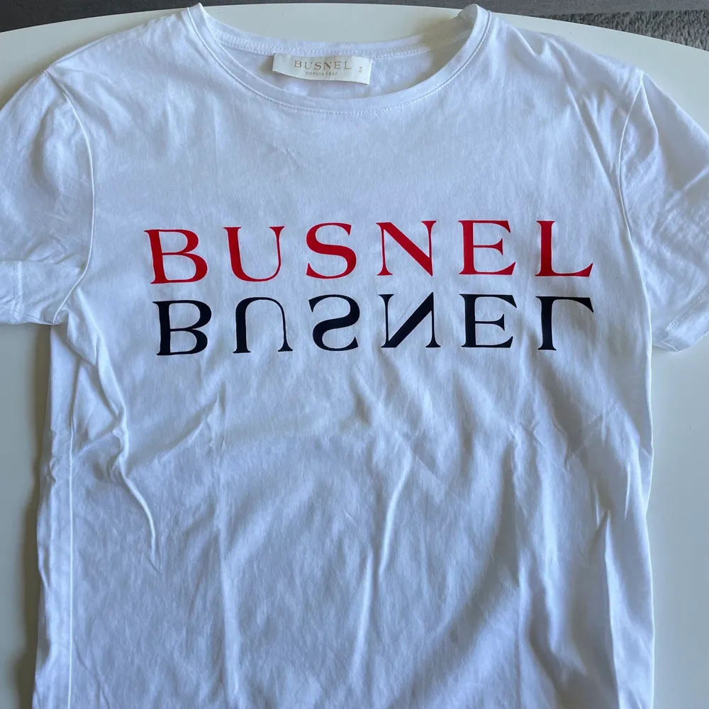 Vit T-shirt med tryck från Busnel i storlek 34. Tröjan är i mycket fint skick & nästintill oanvänd. Pris 250 kr eller högstbjudande.. T-shirts.