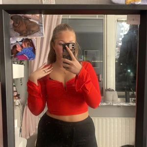 Tröja - En röd Långarmad tröja som knappt andvänts samt att den har lite vidare armar vid händerna samt en vringning med en metal bit inuti 