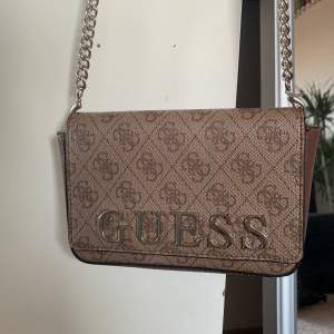 En brun Guess Handväska  , är köpt för några år sedan men kommer inte till användning längere 💗  den är äkta  pris kan diskuteras 