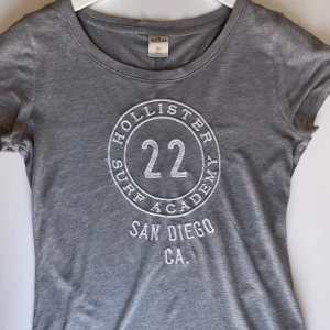 Grå Hollister T-Shirt  - ”Figursydd” dam Hollister T-Shirt. Sitter jättefint på kroppen! Skulle säga att den är mer en S storlek