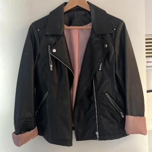 Svart bikerjacka i läderimitation  - Bikerjacka från Only, Använd en gång, så den är som ny. Sitter inte riktigt bra på mig tyvärr. Men den är riktigt snygg. Det rosa innefodralet är 🫶🏽👌🏽😍köpt för 549 kr 