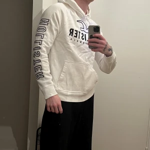 Hollister hoodie - Vit hollister hoodie med tryck fram och på båda ärmar. Använd men i gott skick. St M. Nypris ca: 600:-