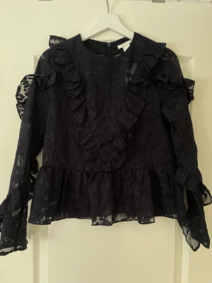 Mörkblå volangblus från H&M - Mörkblå volangblus från H&M Har aldrig kommit till användning och nu vuxit ur den. Lånad bild visar hur den sitter på. Otroligt fint mönster med volangdetaljer över byst samt ärmar.  S- 36  Helt oanvänd med prislapp kvar, därmed utan anmärkningar.  160 kr