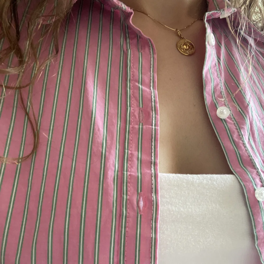 Rosarandig bomullsskjorta som blir en härlig färgklick i din garderob året om! I figursydd modell, med blå detaljer vid ärmarna. Använd bara två gånger så jättefint skick. Nypris 199:-. Skjortor.