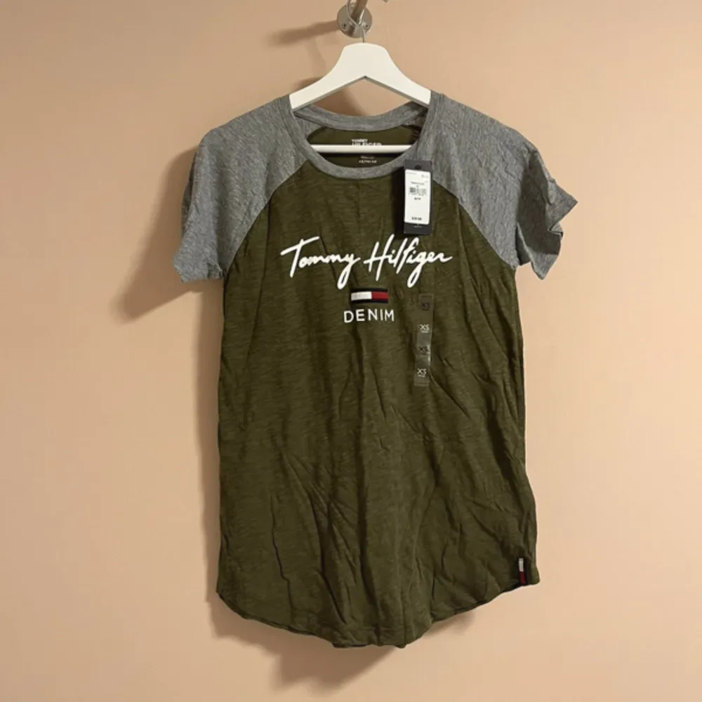 Tommy Hilfiger T-shirt i färgen khaki och grå. Helt ny och oanvänd med prislappen kvar på. Nypris 364 kr ungefär! . T-shirts.