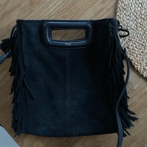 Maje M bag - Nu säljer jag min fina maje M bag i svart mocka. Den är väl använd men ändå i fint skick. Har tyvärr tappat bort bandet som följer med men ni får med det som är med på bilden och det är väldigt likt orginalbandet. Nypris 2600kr, säljer för 900kr.