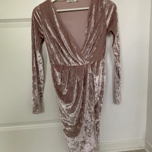 Omlottklänning i sammet  - Klänning med urringning i sammet. Ljusrosa/smutsrosa. Storlek xs från Nelly. Frakt tillkommer!