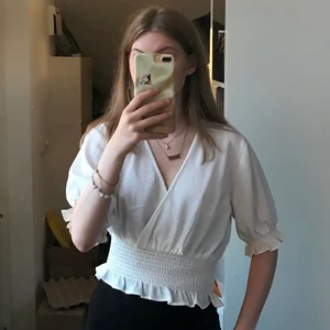 Vit topp - Vit topp från Gina Tricot med djup v-ringning. Har elastiskt runt midjan och armarna för att ge bubbeleffekt runt om. Tjockt elastiskt runt magen. Perfekt sommartopp verkligen 💘