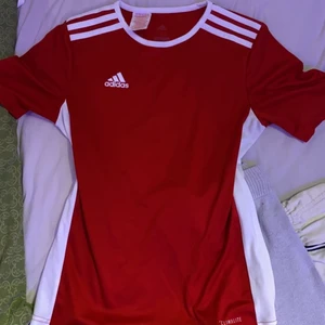 Röd/vit Adidas tränings tshirt  - Storlek 152 alltså M/S passar båda jätte bra, De en tränings tröja som e använd några gånger men tycker inte om färgen röd så säljer den