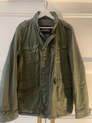 HERNO Cotton Field Jacket Army Green - Jacka med distinkt militär stil är denna fältjacka från Herno. Ett mångsidigt plagg i en mjuk och tvättad bomullskvalitet. Fint skick. Herr, storlek 52. Nypris 7199 kr. Hämtas i Malmö, kan också skickas mot frakt.  Sista bilden för referens.