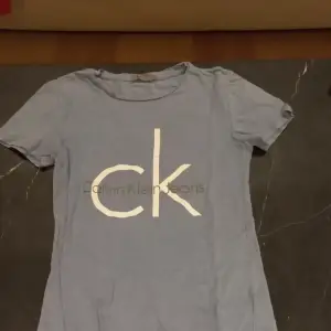 Calvin Klein t-shirt i fin ljusblå färg. St. XS Notera att det finns en liten rosa fläck på vänster sida.