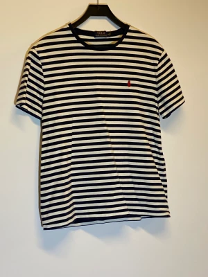 Randig Ralph Lauren T-shirt - Mörkblå vit randig t-shirt från Ralph Lauren, väldigt lite anvönd i bra skick super för sommaren, skriv för frågor!