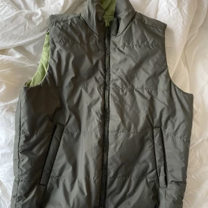 Väst - Väst som går att vända. Den är grön på ena sidan och mörkgrön/grå/svart på andra sidan. Köpt på secondhand men kommer inte till användning längre. Fint skick utan några skador.