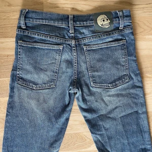 Lågmidjade slimmade jeans  - Ett par lågmidjade jeans i färgen blå med en döskalle som detalj där bak. Dem är i ett bra skick. 🌸