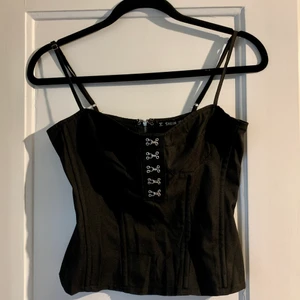 Topp med byglar  - Säljer denna snygga topp då den är för stor för mig! Den har byglar på längden (lite som en korsett) och dragkedja i ryggen🥰