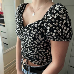 Sommar topp - Jätte söt sommar topp med blommigt mönster ifrån HM. Säljer då den tyvärr inte kommer till användning, nästintill oanvänd. Har snören ifram som gör att man kan justera tröjans längd. Är storlek M men brukar vanligtvis ha storlek S och den passar lagom, är dock resår så den passar för M också. Köparen står för frakten