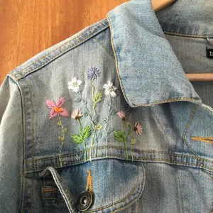 Ljusblå jeansjacka köpt second hand med broderade blommor på. Storlek L men passar som en M om man vill ha den lite oversized.