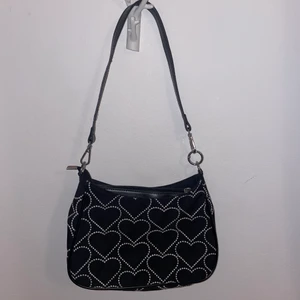 Väska  - En svart väska med vita hjärtan på på båda sidor som inte kommer till användning. I bra skick