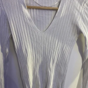 Gina tricot tröja - Säljer denna vita topp från gina tricot då jag inte använder den längre. Den är V-ringad och ribbad med slits vid händerna.