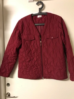 Jacka  - Vinröd tunnare ganska rymlig jacka. Skön och mjuk. V-ringad öppning vid halsen, passar med att använda en vacker scarfs eller halsduk till. Mycket obetydligt använd. Storlek M 