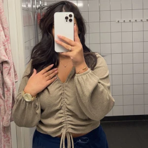 Beige tröja  - Beige tröja från Gina trico i storlek M. Tröjan har snörning fram där man kan justera passformen och längden. Använt 1 gång tidigare.