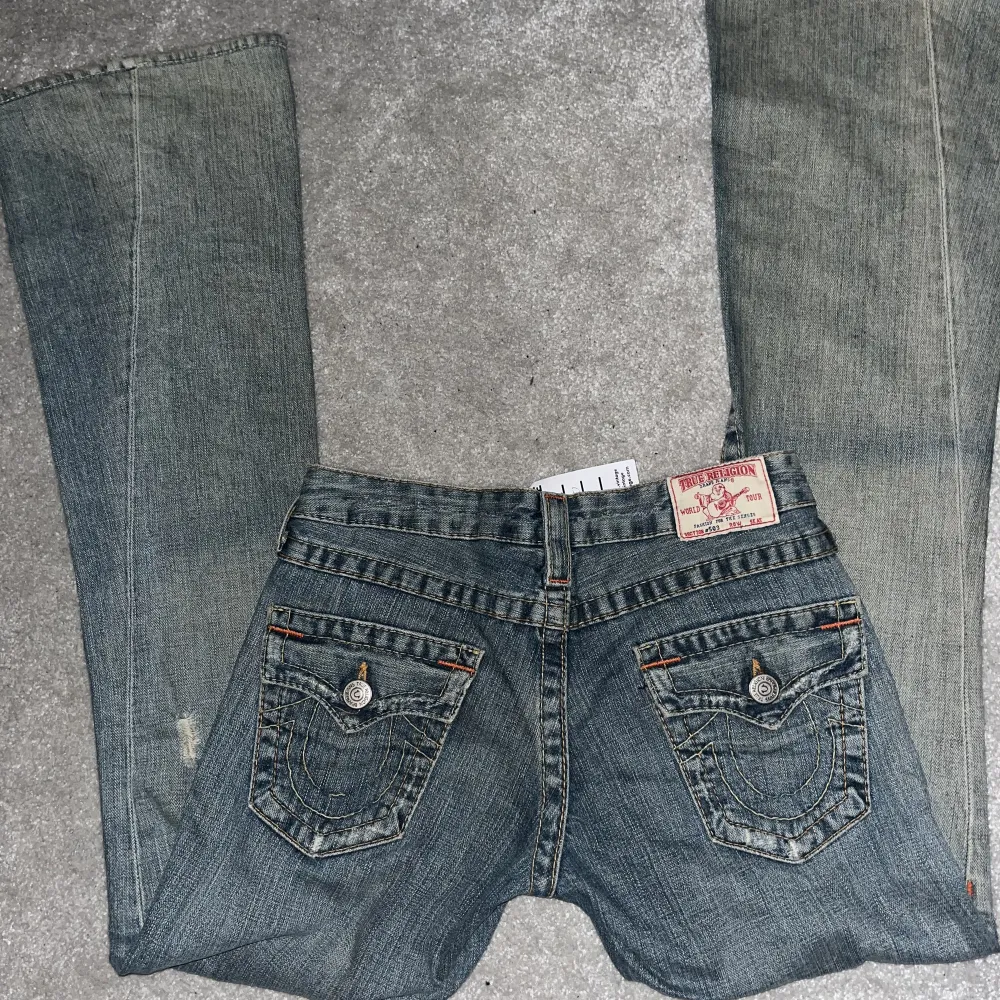 Aaassnygga lågmidjade true religion jeans! i storlek 26, motsvarar XS⭐️Lite vintage ljusblå färg, bootcut,oanvända⭐️Köpta i London för 100 pund (=1270 sek) Måste tyvärr sälja då dom är tighta på mig som har M:( skriv för fler bilder! IBL= 81 cm, midja 36 cm. Jeans & Byxor.