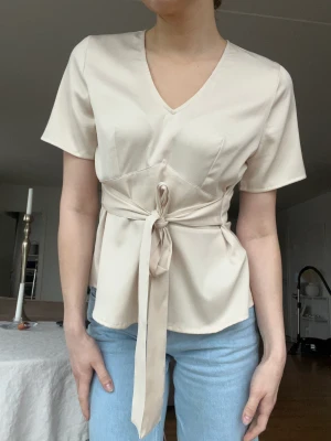 Blus bubbleroom - Oanvänd blus! Satin. Färgen är beige med något inslag av rosa. Går att knyta både bak och fram. Storlek 40 men jag på bilden är S så funkar ända upp till L. NU 50 kr!