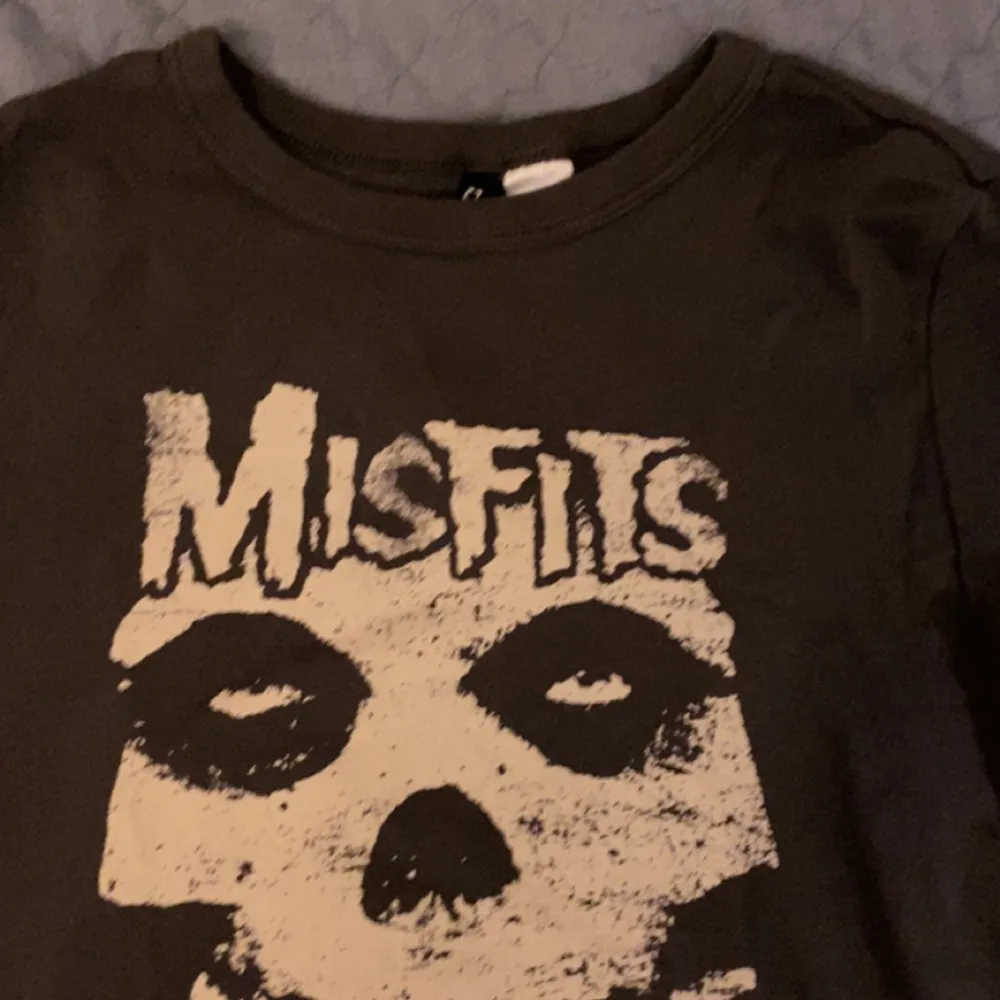 En kort t-shirt från H&M med bandet MisFits på. Jätte skönt, luftigt material och inga fläckar eller skador. Stretchigt material och grå/svart färg.. T-shirts.
