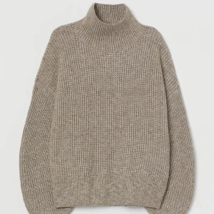 Stickad tröja-inslag av ull  - Stickad tröja med ballongärm. Halvpolo. Gråbeige. Fint skick. Använt sparsamt. Strl XS. 