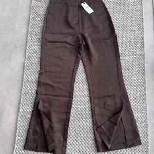 Satin byxor Mango - Oanvända satinbyxor med slits från Mango (psirlapp kvar). Säljs pga för liten storlek. Köparen står för konstnaderna som tillkommer.